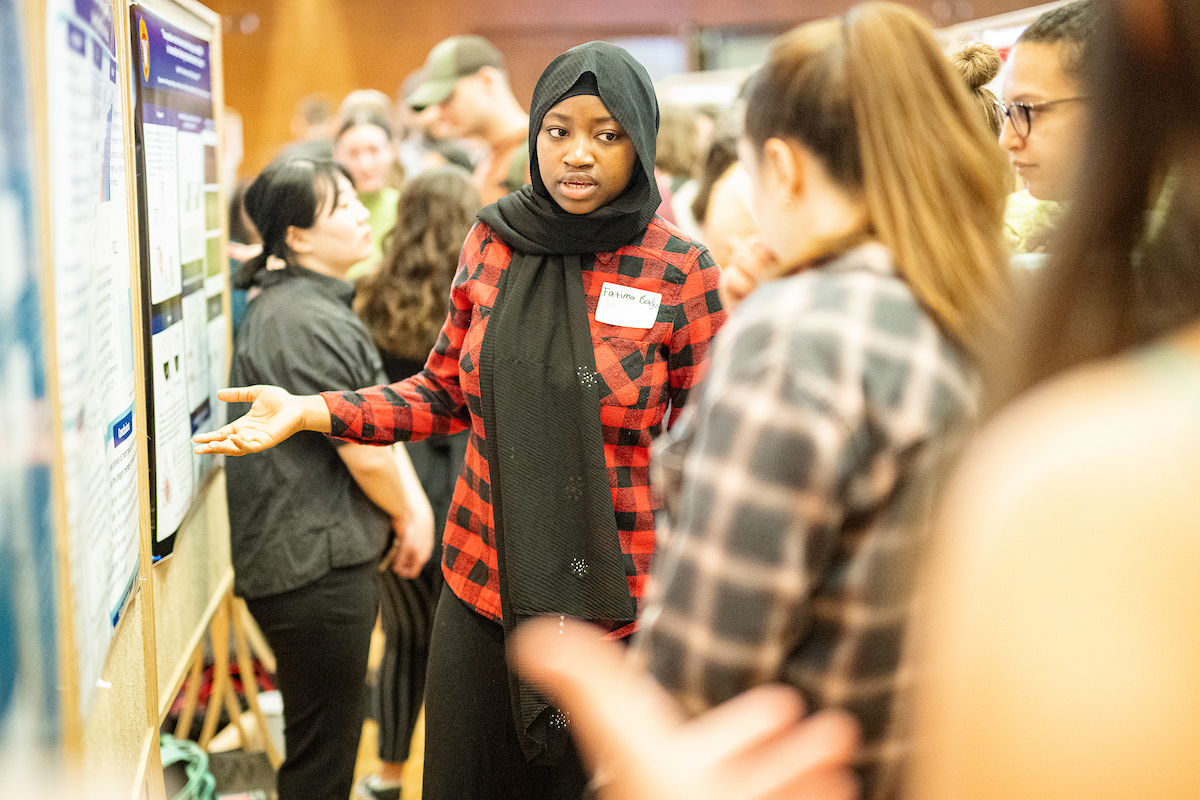 a woman presents her poster at a poster session